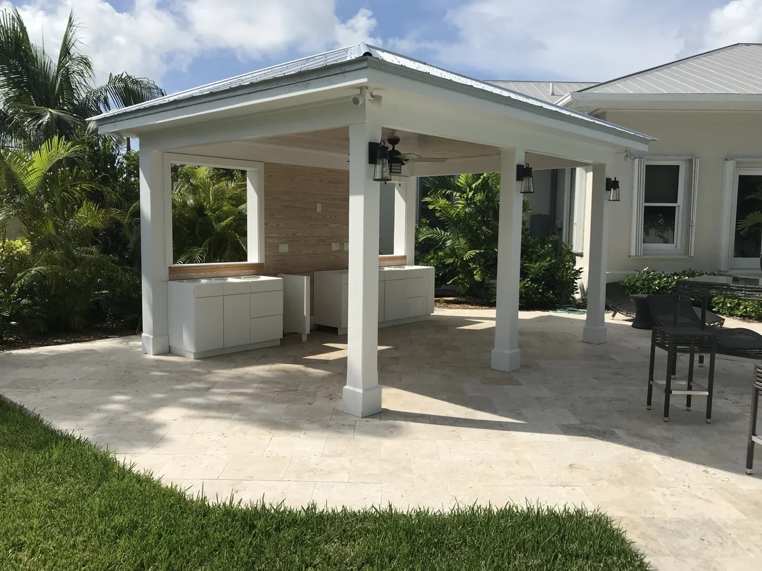 Covered outdoor kitchen pavilion with a solid roof, built-in cabinets, and paved patio.