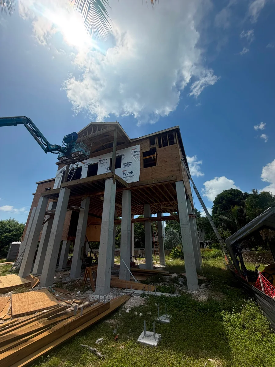 Construction-phase view of elevated residential structure supported by concrete columns.