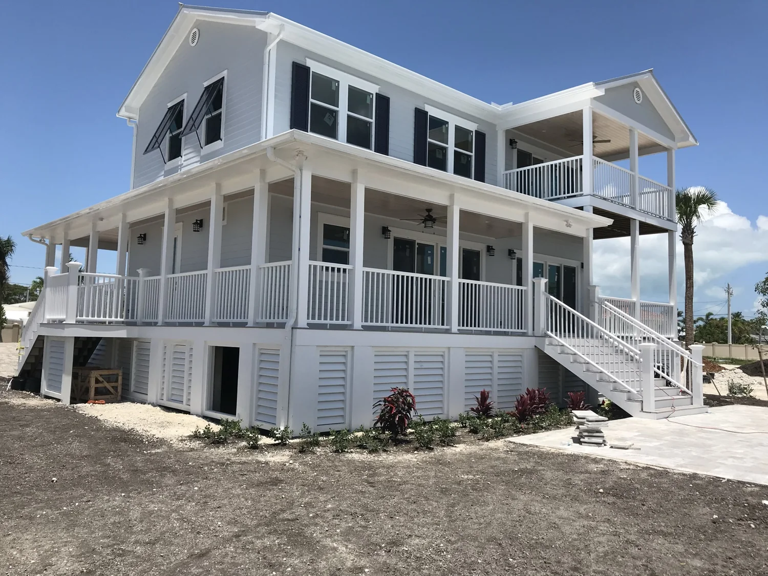 Exterior view of a finished two-story home with wraparound porches and white railings.