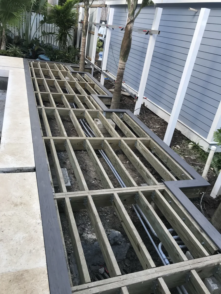 Deck framing and structure under construction next to an existing building.
