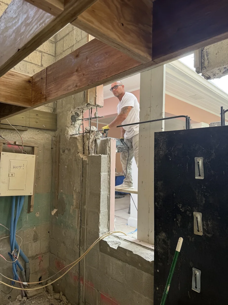 Worker undertaking concrete and masonry demolition at an existing opening.